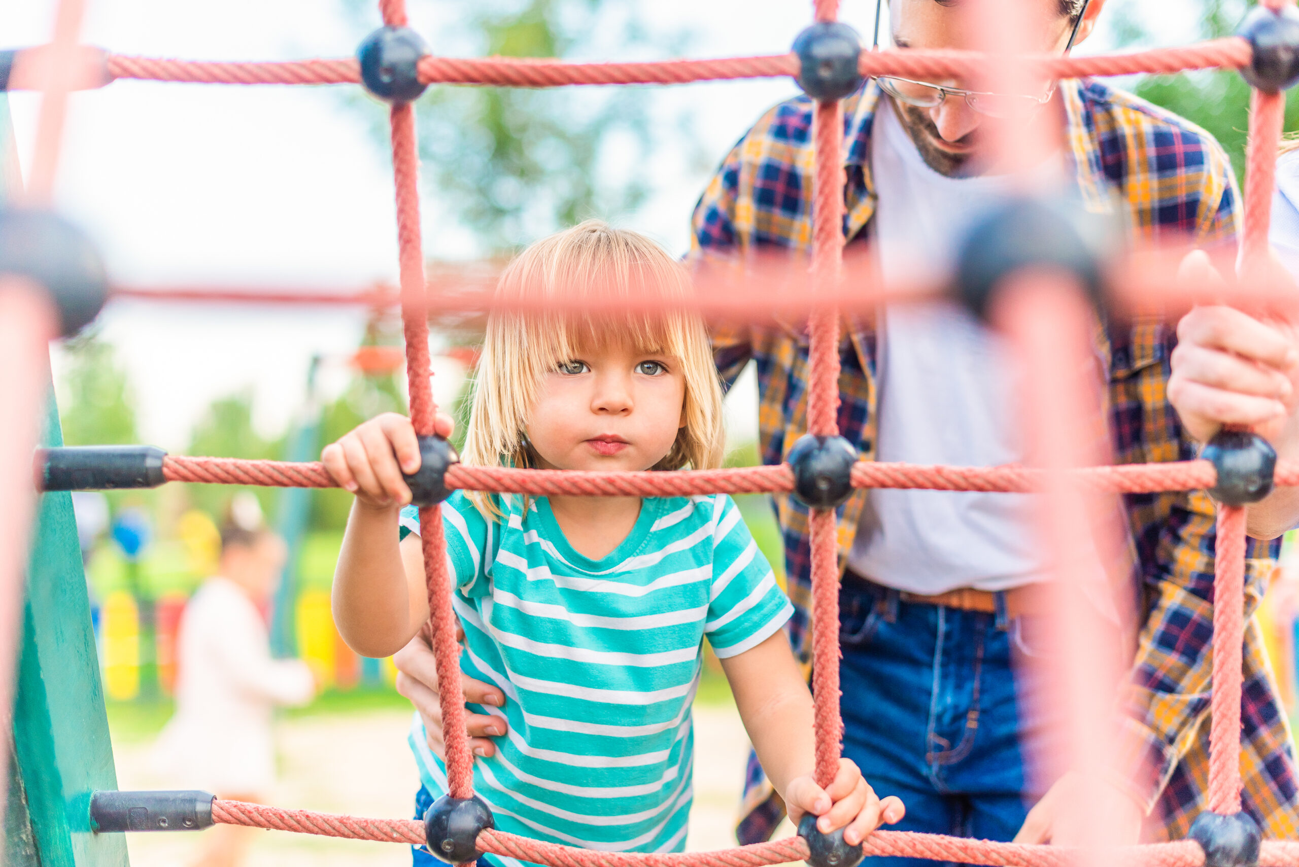 a boy playing on the playground with his young father